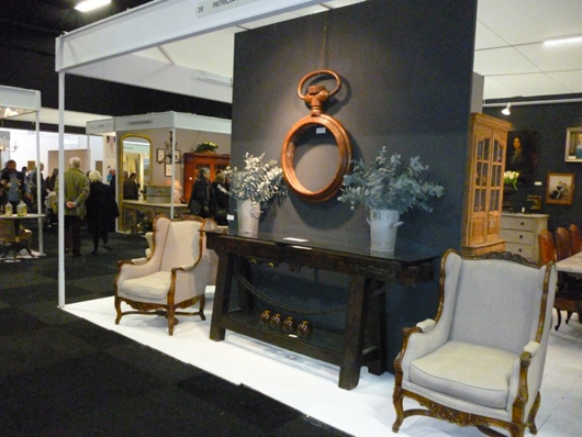 The stand of London decorative dealer Patricia Harvey at the winter Decorative Antiques and Textiles Fair in Battersea Park in January. The giant carved wood pocket watch shop sign was priced at £2,800 ($4,400) and the old French industrial console table below it was on sale at £5,500 ($8,640). Image: Auction Central News.